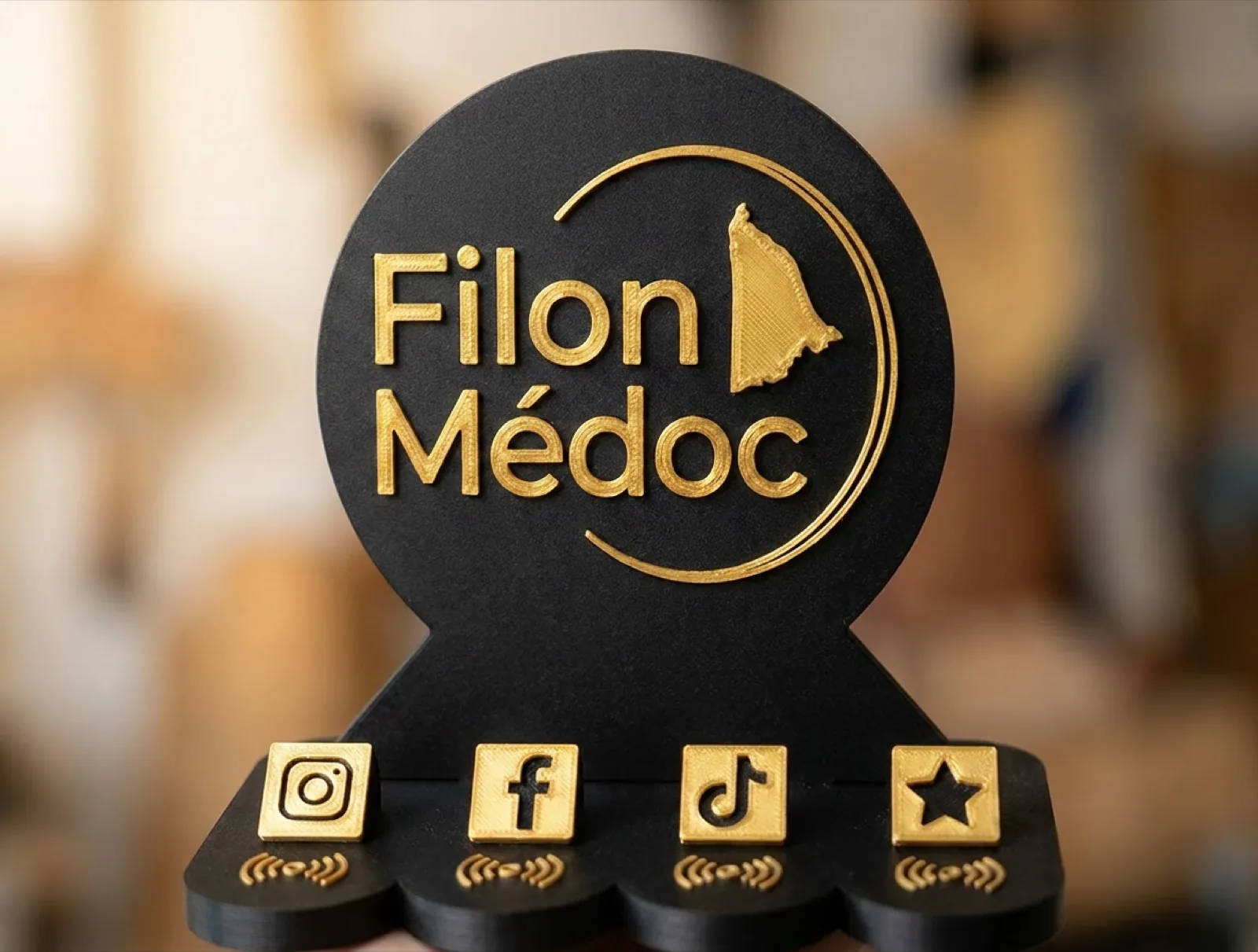 Stand NFC Filon Médoc en PLA noir et or, avec son logo en relief et ses 4 logos réseaux clipables (Instagram, Facebook, TikTok, avis Google) au-dessus de leurs puces NFC