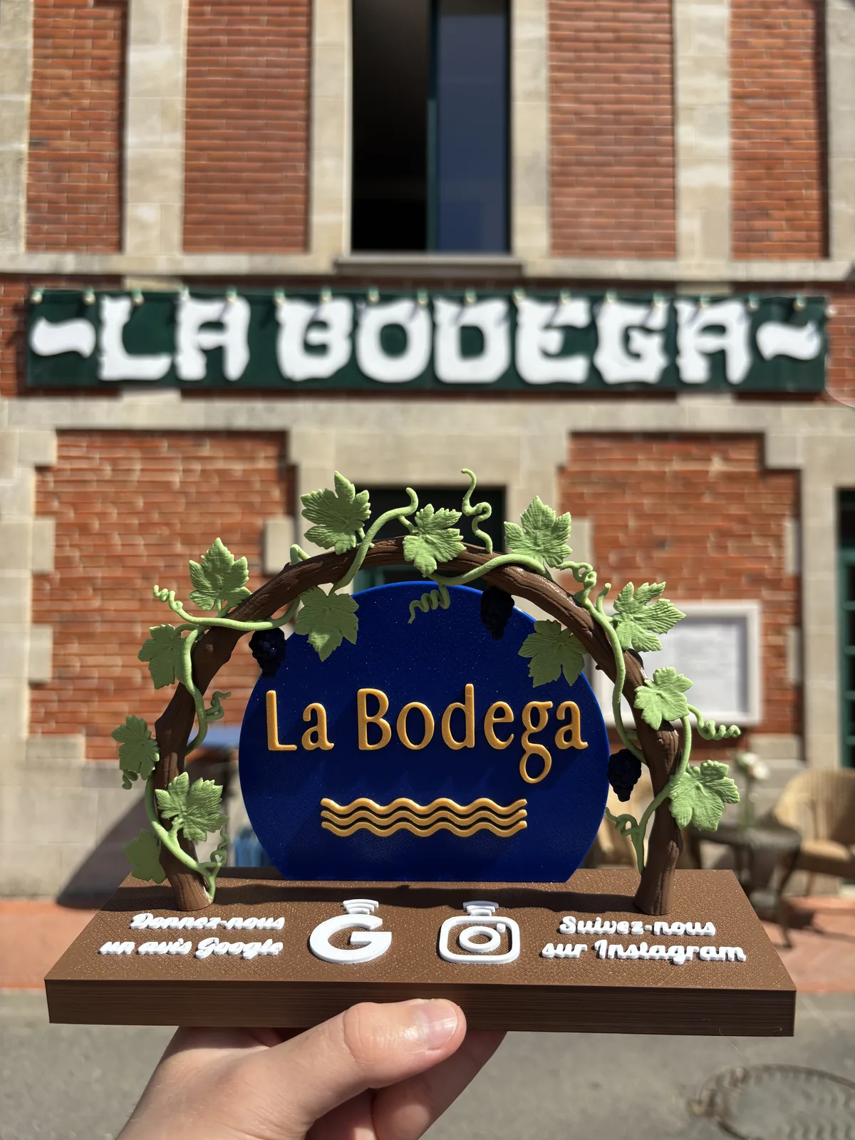 NFC stand for the La Bodega bar and restaurant in Soulac-sur-Mer: raised vine arch, blue and gold sign, 2 contactless shortcuts to Google reviews and Instagram