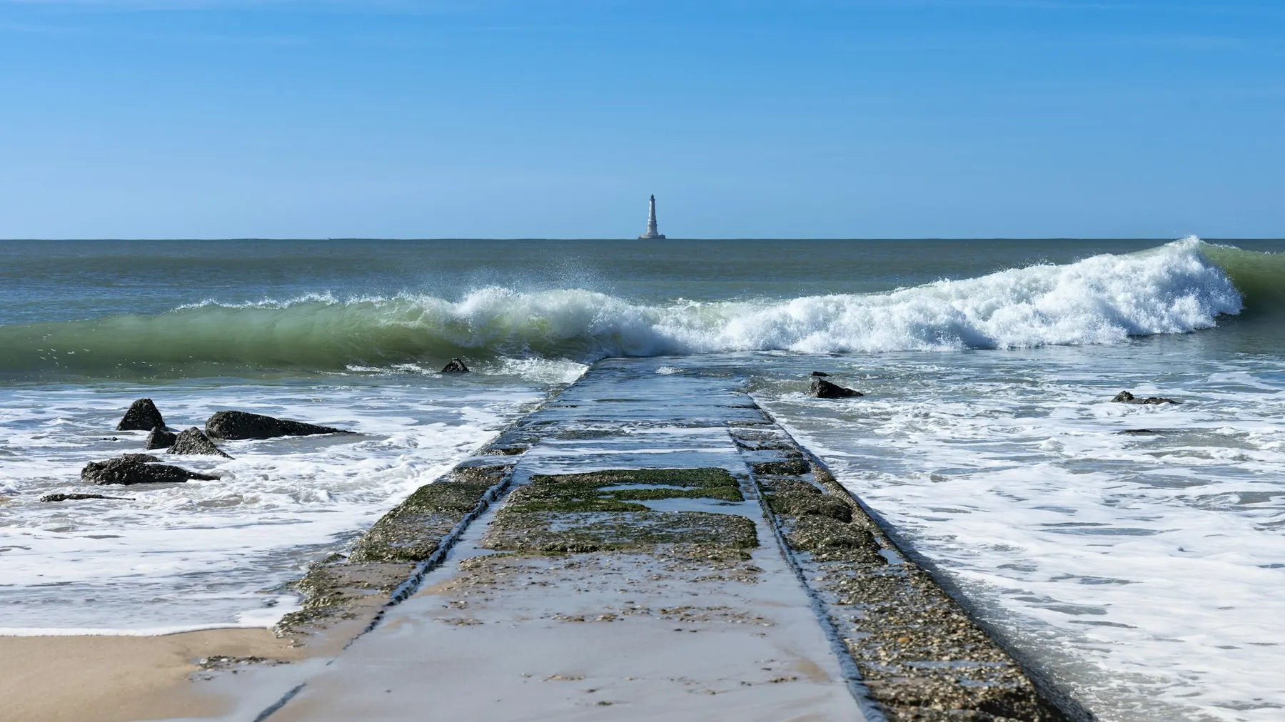 Jetty facing the ocean at the tip of the Médoc, Cordouan lighthouse on the horizon